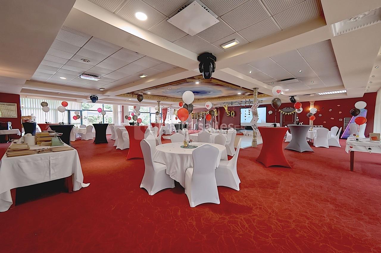 Un espace grandiose et festif au Salon Impérial Salle décorée pour un événement avec tables rondes, nappes blanches, ballons colorés et éclairage chaleureux.