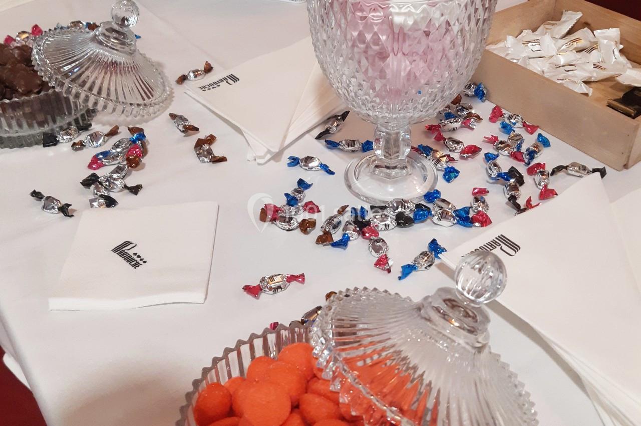 Une pause  Bonbonnières en verre remplies de sucreries colorées sur une table blanche avec des serviettes et des bonbons dispersés.