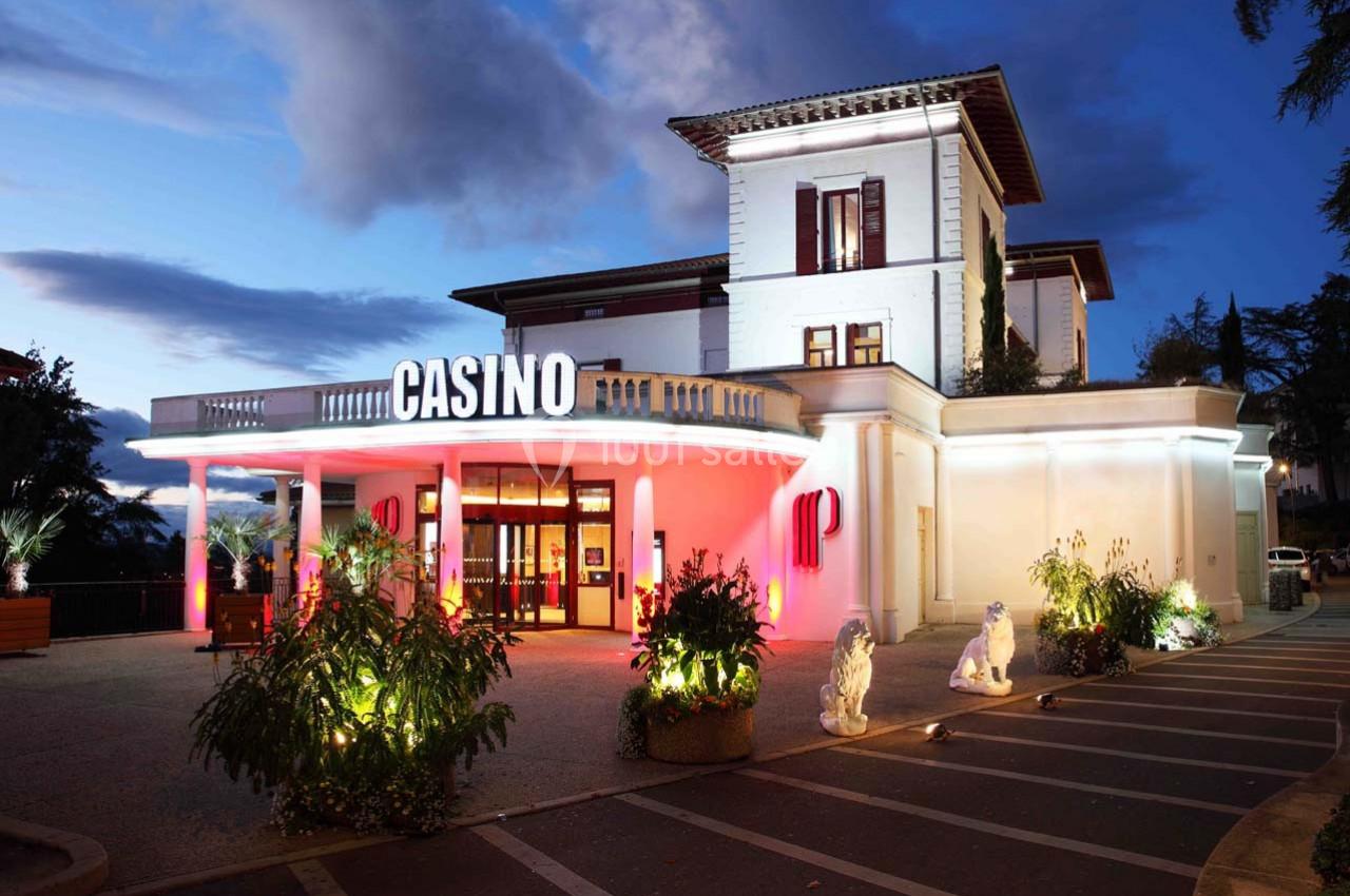 Location salle Saint-Galmier (Loire) - Casino de Saint-Galmier #8 Façade éclairée d'un casino de style classique avec entrée principale entourée de plantes et statues, en soirée.