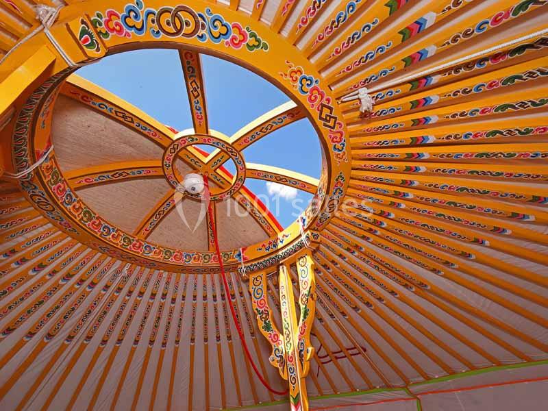 Structure intérieure colorée d'une yourte traditionnelle avec des motifs décoratifs et un ciel visible à travers l'ouverture…