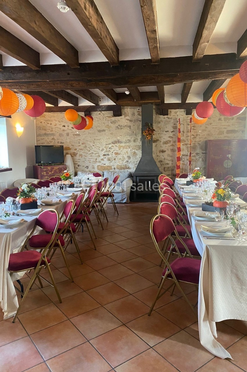Salle de réception décorée avec des tables dressées, des chaises rouges et des lanternes suspendues sous un plafond en…