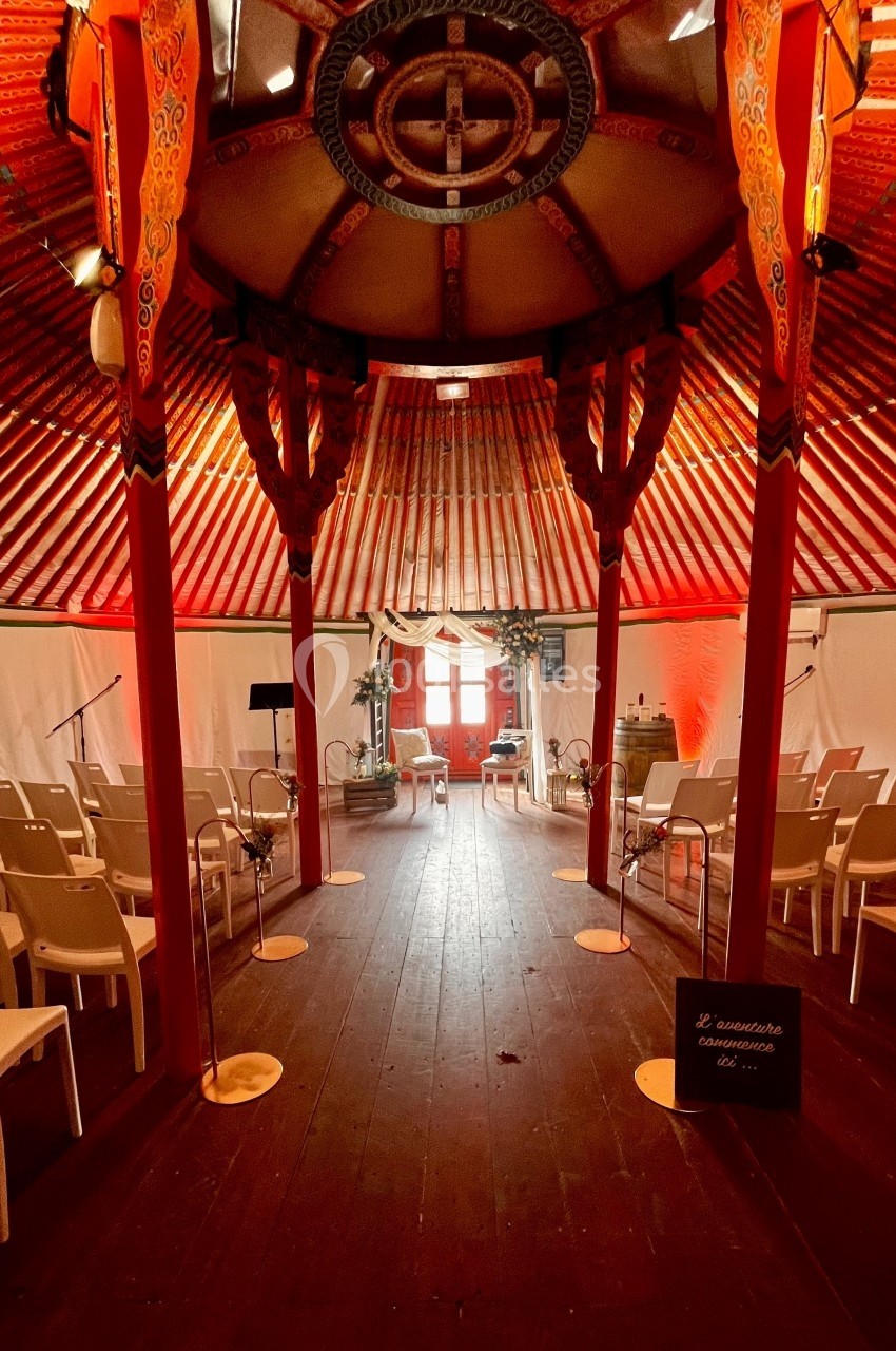 Intérieur d'une tente décorée de motifs traditionnels, aménagée avec des chaises blanches pour un événement.