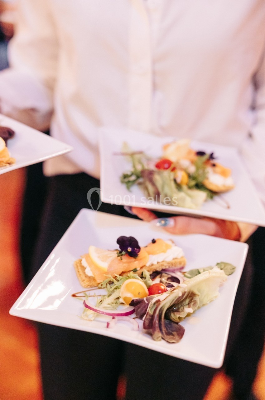 Assiette de hors-d'œuvre composée de saumon fumé, crème, légumes frais et fleurs comestibles.