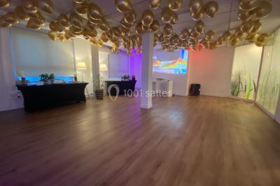 Miniature Location salle Paris 8 (Paris) - L'Appart Terrasse des Champs #4 Salle lumineuse avec parquet, plafond décoré de ballons dorés, table avec plantes et vue sur des bâtiments urbains.