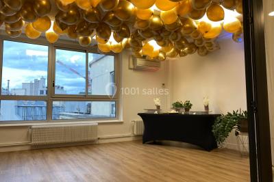 Miniature Location salle Paris 8 (Paris) - L'Appart Terrasse des Champs #13 Salle lumineuse avec parquet, plafond décoré de ballons dorés, table avec plantes et vue sur des bâtiments urbains.