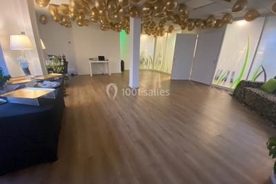 Miniature Location salle Paris 8 (Paris) - L'Appart Terrasse des Champs #14 Salle lumineuse avec parquet, plafond décoré de ballons dorés, table avec plantes et vue sur des bâtiments urbains.