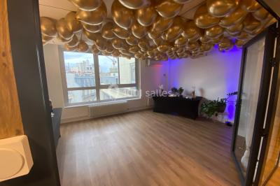 Miniature Location salle Paris 8 (Paris) - L'Appart Terrasse des Champs #15 Salle lumineuse avec parquet, plafond décoré de ballons dorés, table avec plantes et vue sur des bâtiments urbains.