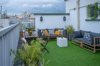 Miniature Location salle Paris 8 (Paris) - L'Appart Terrasse des Champs #2 Salle lumineuse avec parquet, plafond décoré de ballons dorés, table avec plantes et vue sur des bâtiments urbains.