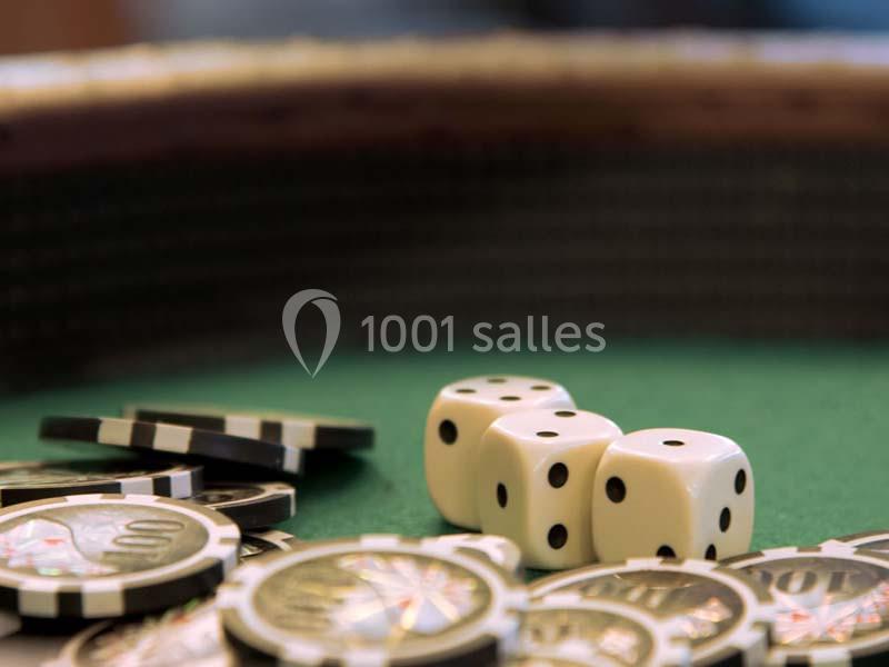 Des jetons de casino et deux dés blancs posés sur une table de jeu verte.