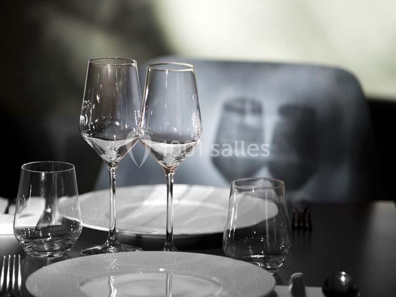 Deux verres à vin et deux verres à eau disposés sur une table élégamment dressée avec des assiettes blanches.