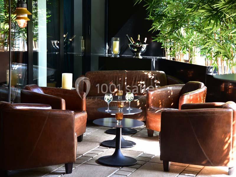 Quatre fauteuils en cuir disposés autour de tables basses dans un espace lumineux avec des plantes en arrière-plan.