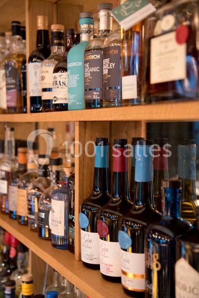 Bouteilles d'alcools variés disposées sur des étagères en bois dans un espace de présentation.