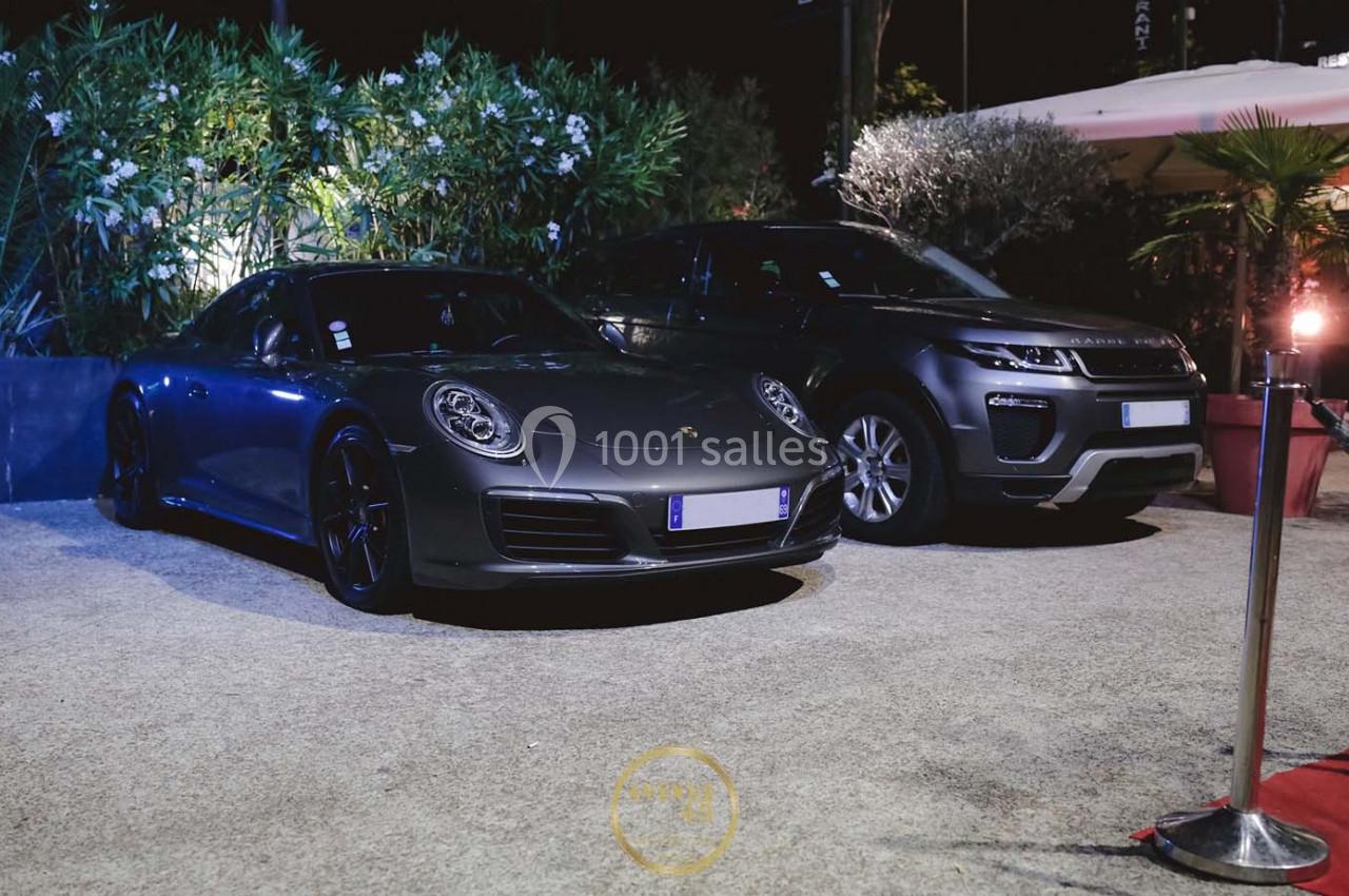 Deux voitures de luxe, une sportive grise et un SUV gris foncé, stationnées côte à côte en extérieur de nuit.