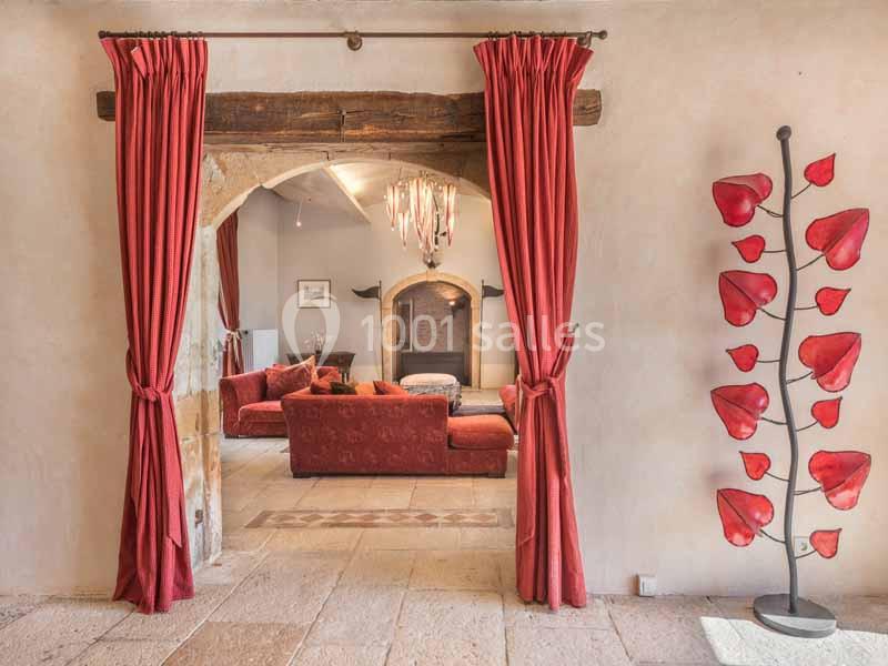 Vue d'un salon chaleureux avec canapés rouges, cheminée, rideaux assortis et sculpture décorative en forme de feuilles…