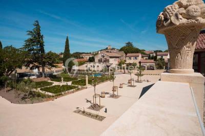Une voiture bleue traverse un chemin bordé de vignes et de murets en pierre sous un ciel dégagé.
