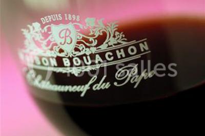 Une voiture bleue traverse un chemin bordé de vignes et de murets en pierre sous un ciel dégagé.