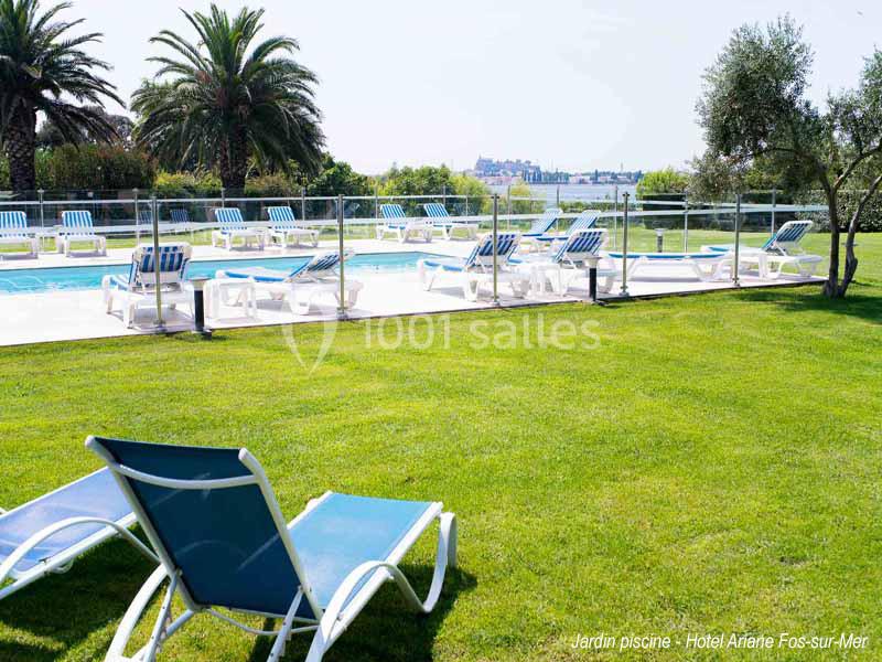 Chaises longues autour d'une piscine extérieure entourée de pelouse, avec des palmiers et une vue dégagée.