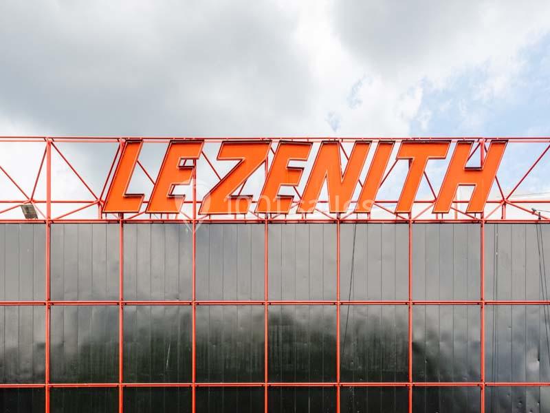Façade vitrée avec le nom ’Le Zénith’ écrit en grandes lettres rouges sur une structure métallique.
