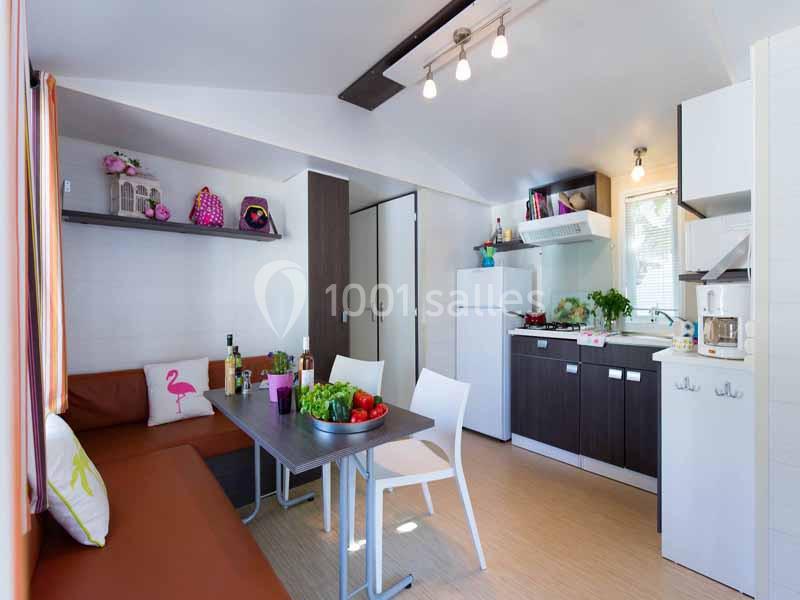 Intérieur lumineux d'une petite cuisine ouverte avec coin salon, table à manger et décoration colorée.