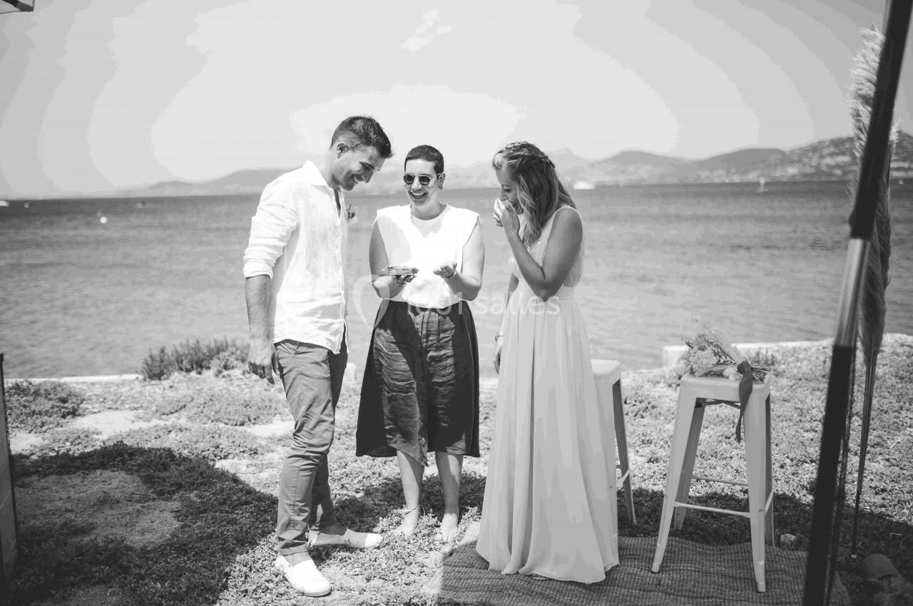 Trois personnes souriantes discutent près d'un plan d'eau, dans un cadre extérieur ensoleillé.