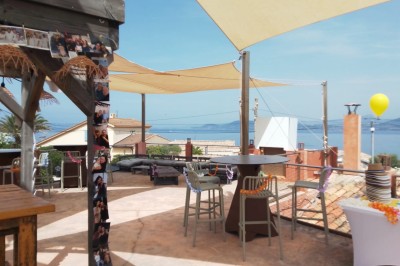 Miniature Location salle Hyères (Var) - La Réserve Hyères - Giens #5 Des personnes dansent en couple sur une piste éclairée par des lumières colorées, tandis que d'autres sont assises autour.