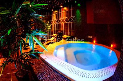 Miniature Aphrodite SPA Des personnes dansent en couple sur une piste éclairée par des lumières colorées, tandis que d'autres sont assises autour.