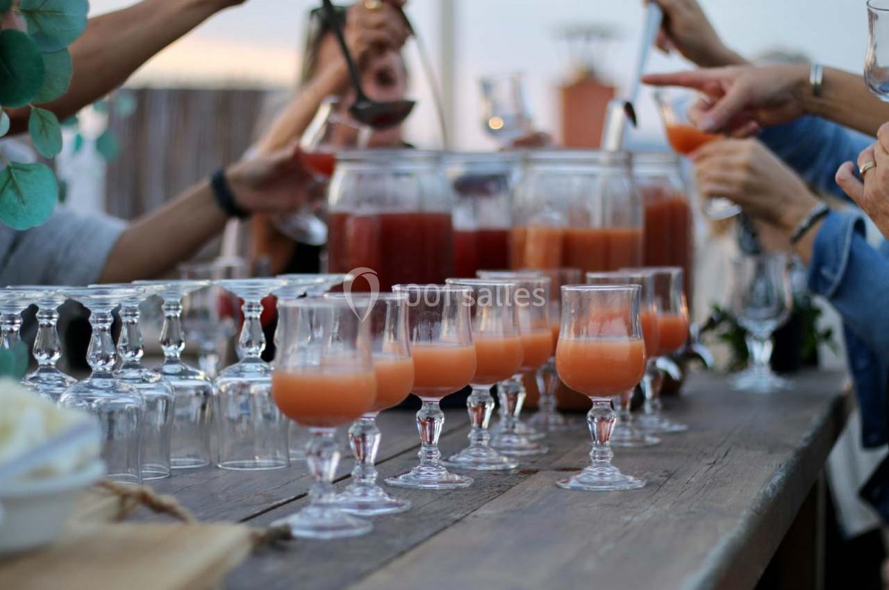 Location salle Hyères (Var) - La Réserve Hyères - Giens #8 Des verres de cocktail remplis sur une table en bois, entourés de mains servant des boissons.