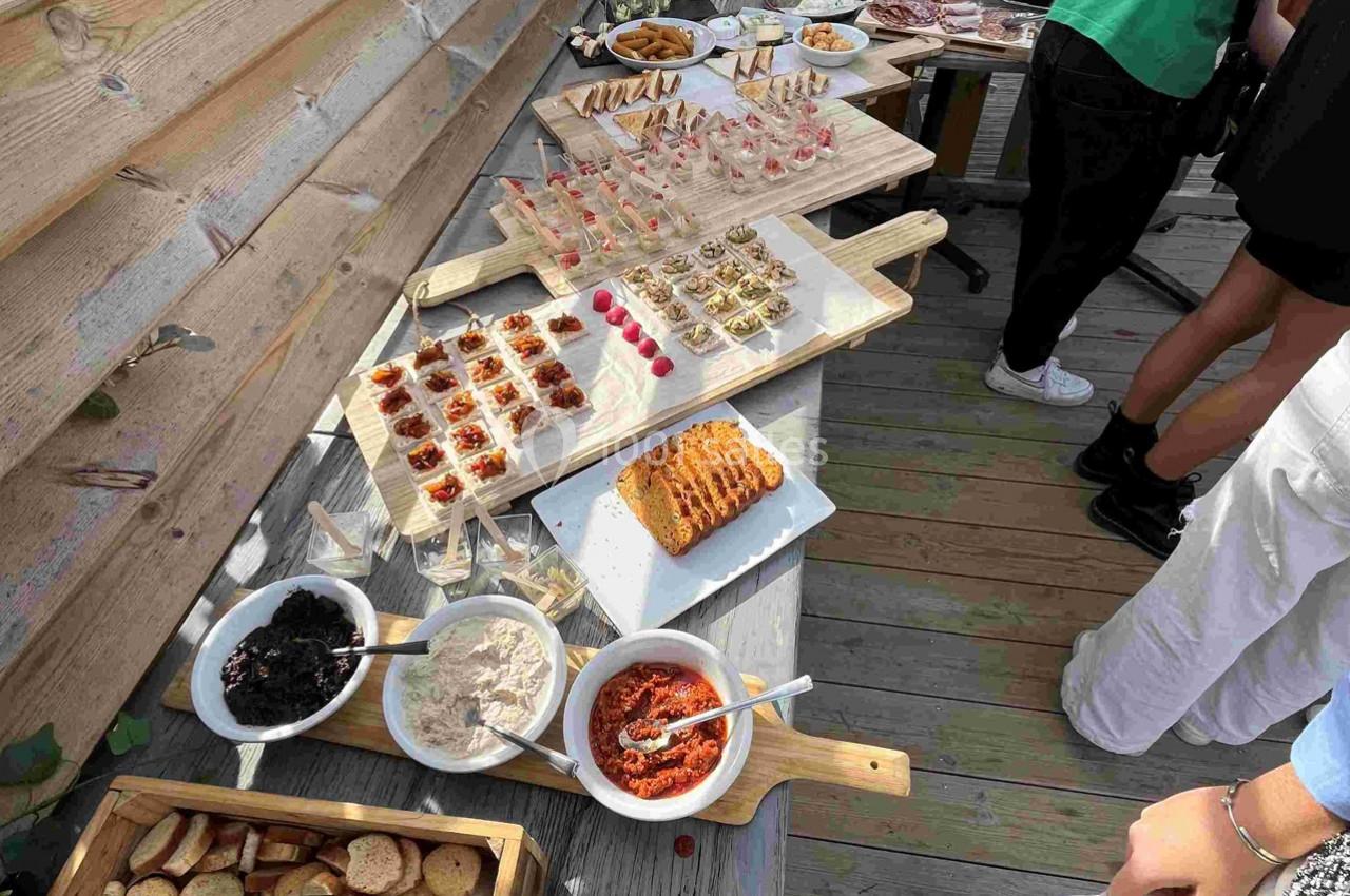 Location salle Hyères (Var) - La Réserve Hyères - Giens #6 Buffet en extérieur avec divers amuse-bouches, tartinades, pain et condiments disposés sur des planches en bois.