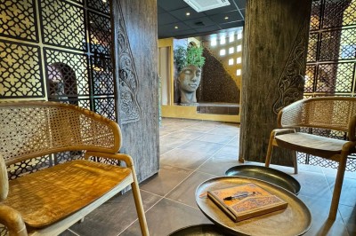 Miniature Aphrodite SPA Salle de massage tamisée avec deux tables recouvertes de draps bruns et une décoration murale apaisante.