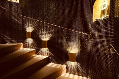 Miniature Aphrodite SPA Salle de massage tamisée avec deux tables recouvertes de draps bruns et une décoration murale apaisante.