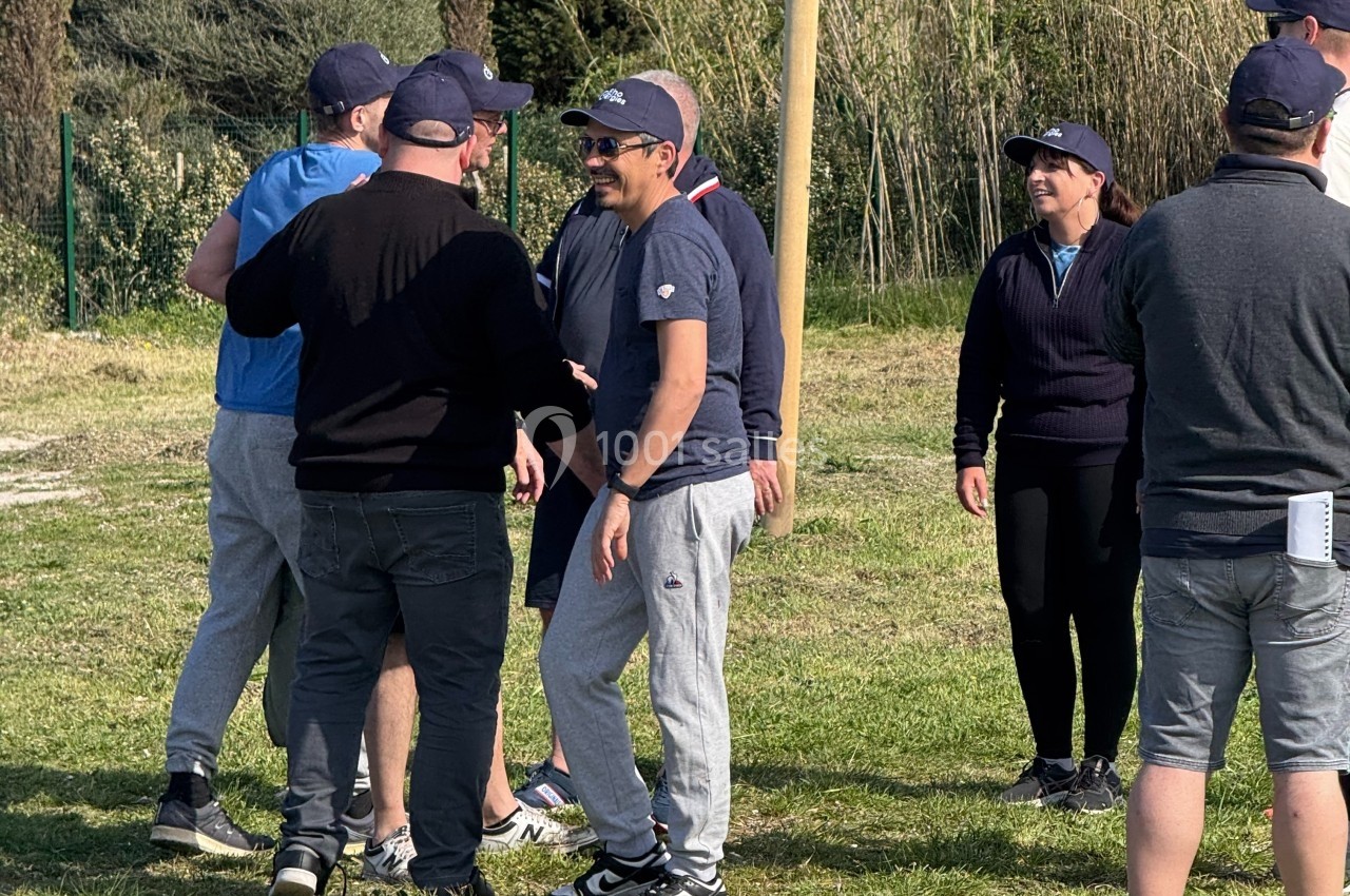 Teambuilding sur le terrain Les Pieds dans l'Eau Un groupe de personnes discutant et souriant en extérieur sur une pelouse, entouré de végétation.