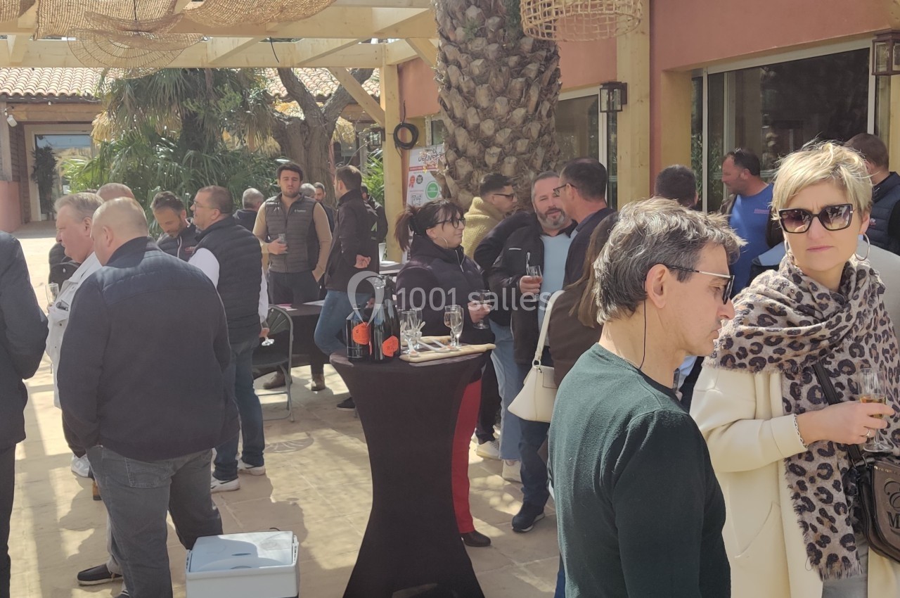 Terrasse restaurant La Réserve Un groupe de personnes discute en extérieur sous une pergola, avec des tables et des décorations en osier.