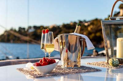 Cabine de bateau avec deux lits simples, linge de lit beige et rouge, éclairage intégré et hublots.