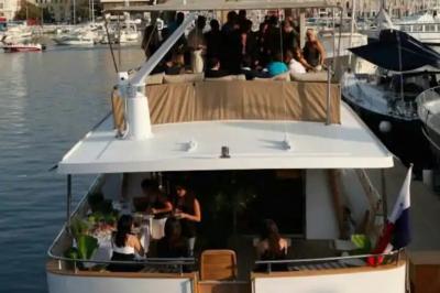 Cabine de bateau avec deux lits simples, linge de lit beige et rouge, éclairage intégré et hublots.