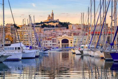 Cabine de bateau avec deux lits simples, linge de lit beige et rouge, éclairage intégré et hublots.