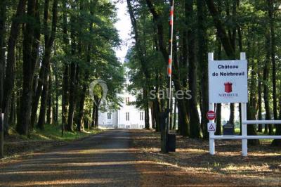 Vue d'un couloir lumineux menant à une chambre avec un lit, des murs clairs et un tapis au sol.