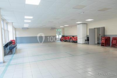 Vue d'un couloir lumineux menant à une chambre avec un lit, des murs clairs et un tapis au sol.