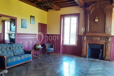 Vue d'un couloir lumineux menant à une chambre avec un lit, des murs clairs et un tapis au sol.