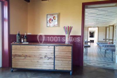 Vue d'un couloir lumineux menant à une chambre avec un lit, des murs clairs et un tapis au sol.