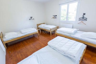 Vue d'un couloir lumineux menant à une chambre avec un lit, des murs clairs et un tapis au sol.