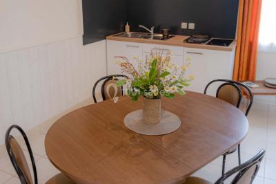 Vue d'un couloir lumineux menant à une chambre avec un lit, des murs clairs et un tapis au sol.
