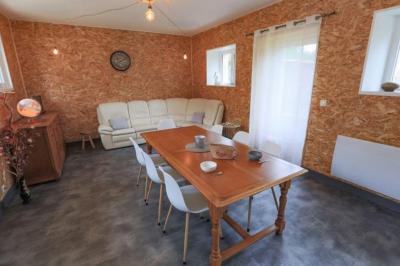 Vue d'un couloir lumineux menant à une chambre avec un lit, des murs clairs et un tapis au sol.