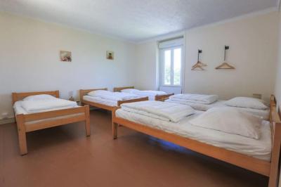 Vue d'un couloir lumineux menant à une chambre avec un lit, des murs clairs et un tapis au sol.