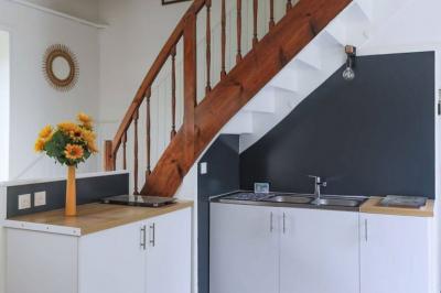 Vue d'un couloir lumineux menant à une chambre avec un lit, des murs clairs et un tapis au sol.