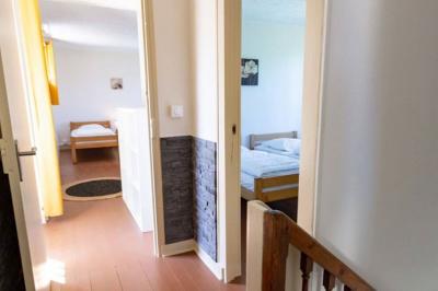 Vue d'un couloir lumineux menant à une chambre avec un lit, des murs clairs et un tapis au sol.