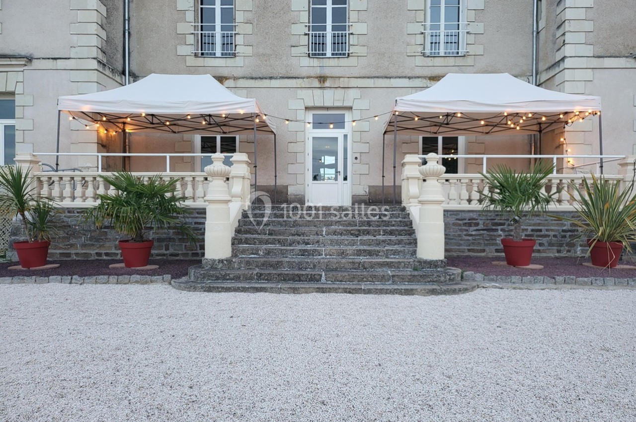 Location salle Chaumes-en-Retz (Loire-Atlantique) - Château de Noirbreuil #6 Entrée d'un bâtiment ancien avec escaliers en pierre, deux tonnelles blanches et des plantes en pots rouges.