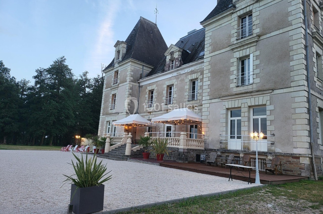 Location salle Chaumes-en-Retz (Loire-Atlantique) - Château de Noirbreuil #3 Façade d'un château ancien avec terrasse aménagée, éclairages et mobilier extérieur, entouré de végétation.