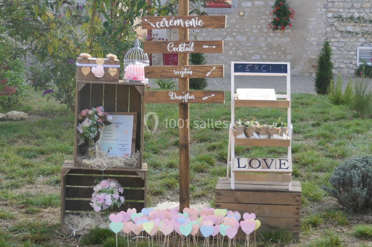 Décoration champêtre avec panneaux directionnels, fleurs, et accessoires pour un événement en extérieur.