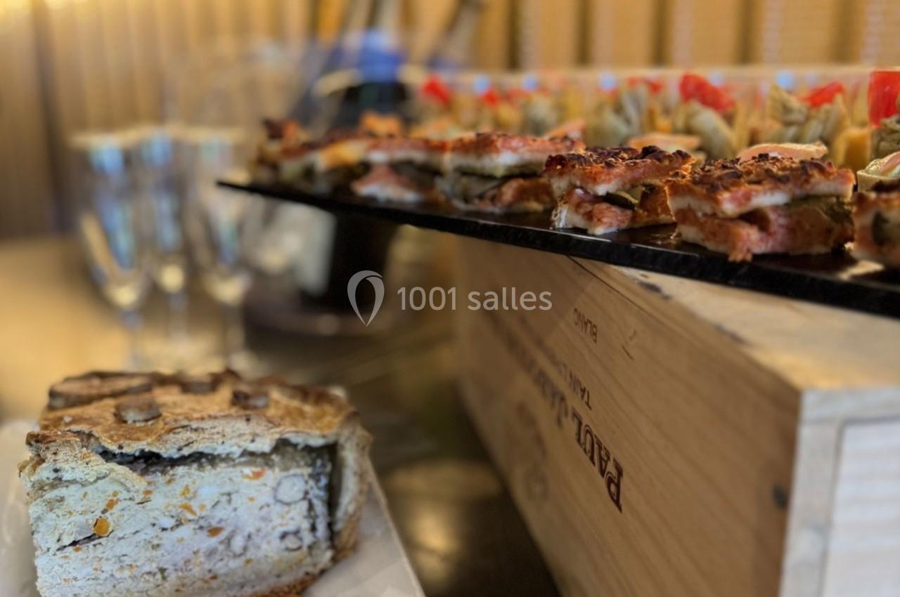Plateau de bouchées apéritives et pâté en croûte sur une table, avec des flûtes à champagne en arrière-plan.
