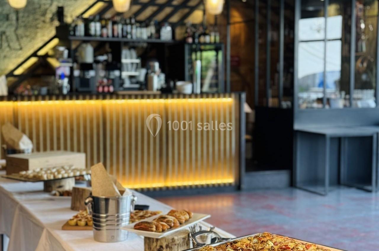 Buffet avec viennoiseries, pizzas et desserts disposés sur des tables dans un restaurant au décor moderne.